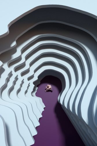 Digital generated image of man sitting on cube inside multi layered head silhouette.