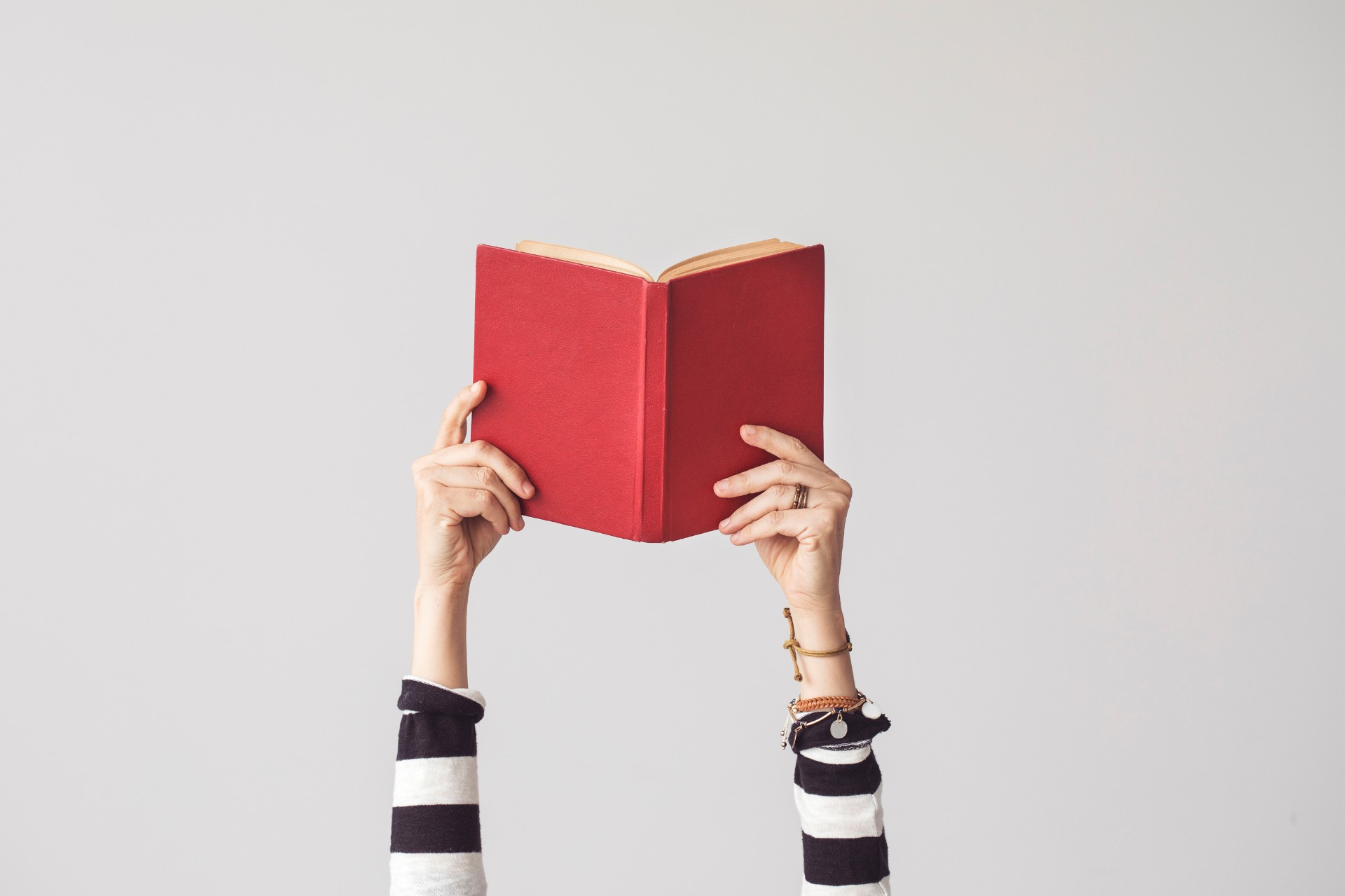 Woman's hands holding a red book up in the air