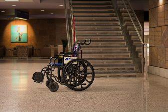A wheelchair sits at the bottom of steep chairs in a public building