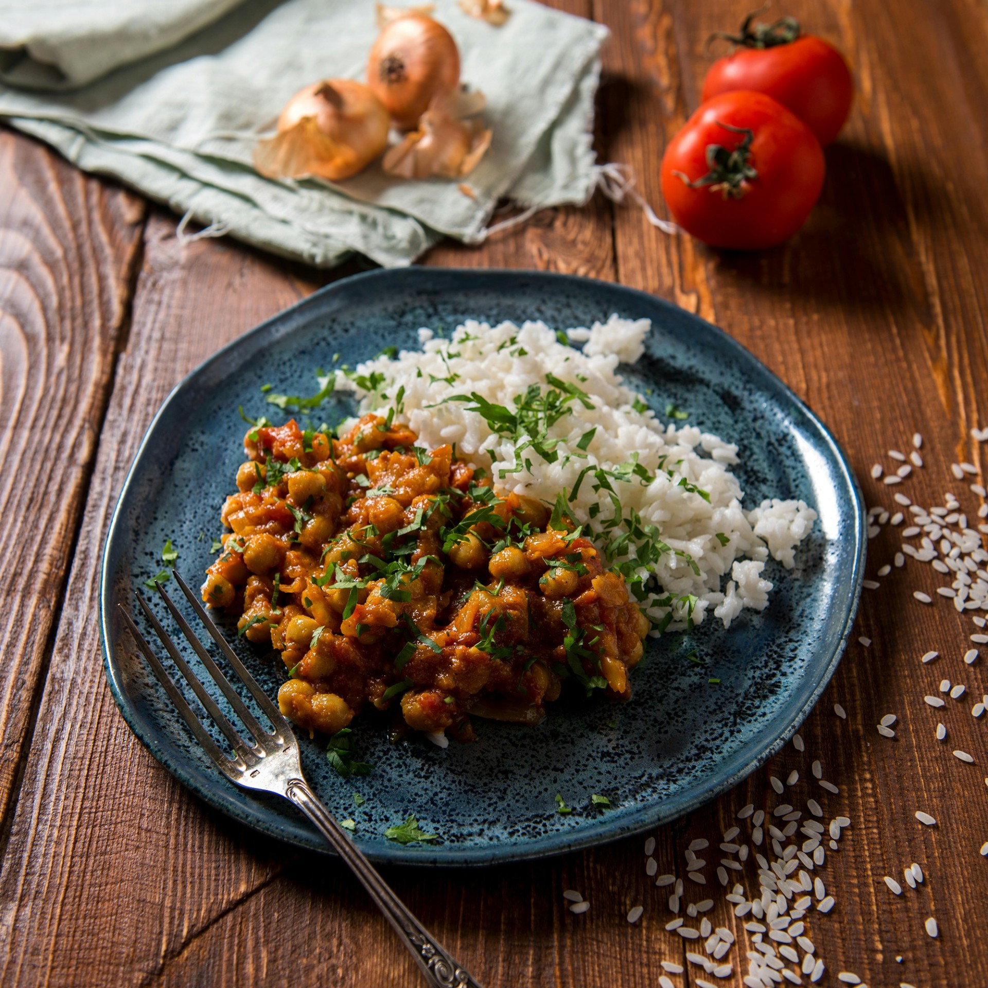 A beautifully plated meal of chickpea curry and rice on a blue plate