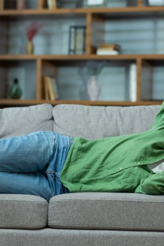 An elderly woman is lying on the sofa at home and suffers from a headache, pressure, tension. holding his head Stress, got sick.