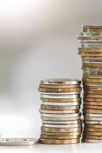 Australian currency held by a woman with braids outdoors in a lush park.