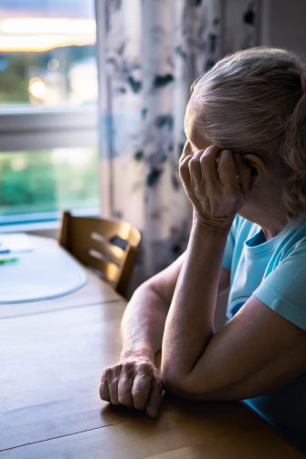 Sad old woman. Depressed lonely senior lady with alzheimer, dementia, memory loss or loneliness. Elder person looking out the home window. Sick patient with disorder. Pensive grandma. Widow with grief