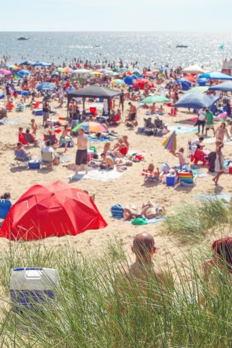 A beach crowded with colourful umbrellas and lots of people