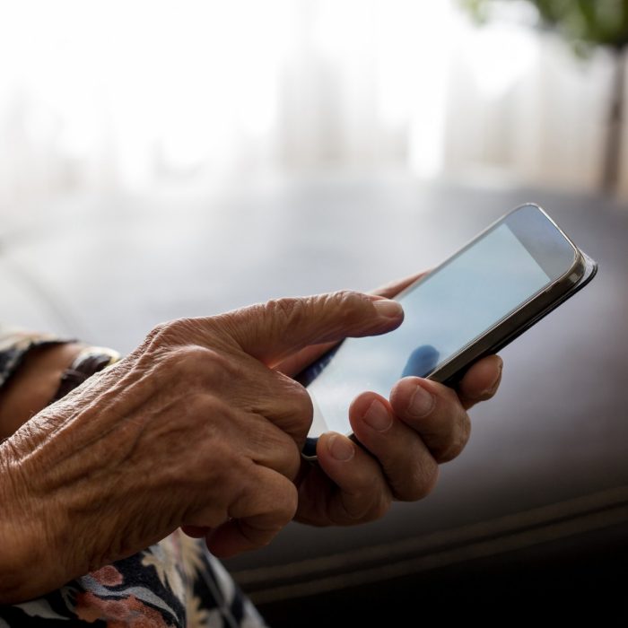 Old woman hands with mobile phone, closeup shot