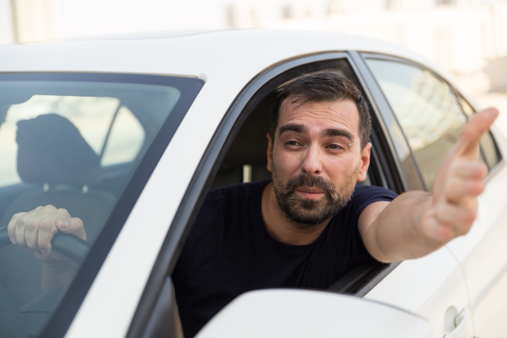 A man gestures angrily through his car window.