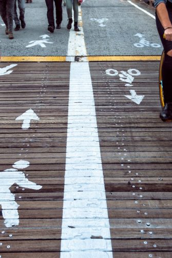 Pedestrian and bicycle riders sharing the street lanes with road marking in the city. People walking and riding on bicycle on city street.