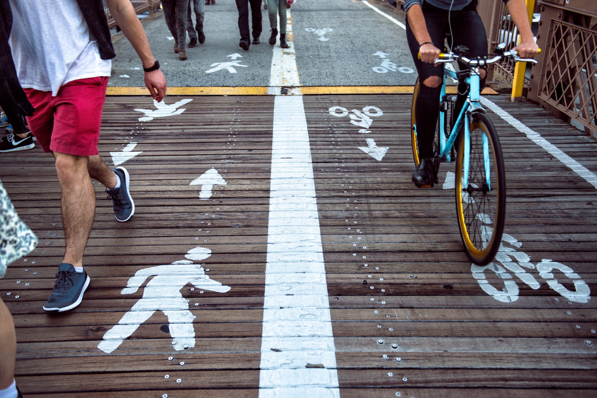 Pedestrian and bicycle riders sharing the street lanes with road marking in the city. People walking and riding on bicycle on city street.