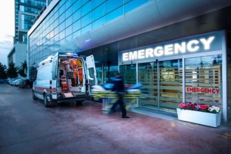 Paramedics taking patient on stretcher from ambulance to hospital emergency department