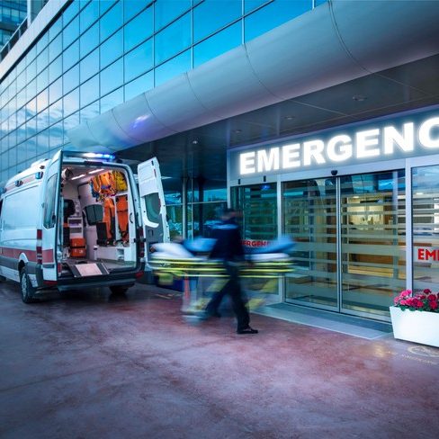 Paramedics taking patient on stretcher from ambulance to hospital emergency department