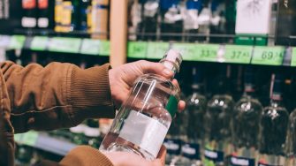 Shopper holds bottle of alcohol in store stock