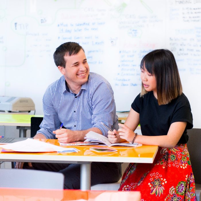Photograph of a conversation between two adults discussing the disability inclusion plan