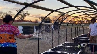 Two people helping with watering the community garden and installing the wicked beds.