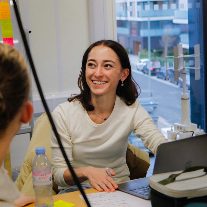 A smiling student collaborating with peers at a desk during a work-integrated learning session.