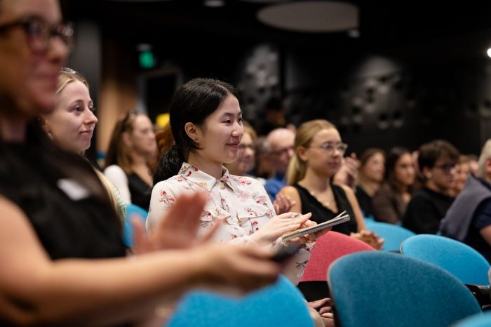 Audience members smiling and clapping at the Creative Conversations panel event on Ai