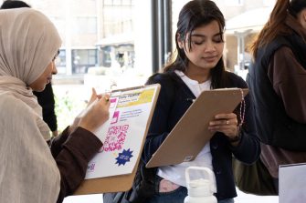 Two students engaging with ADA Stories project at Diversity Festival 2024 by writing a story about their name to hang on the wishing tree