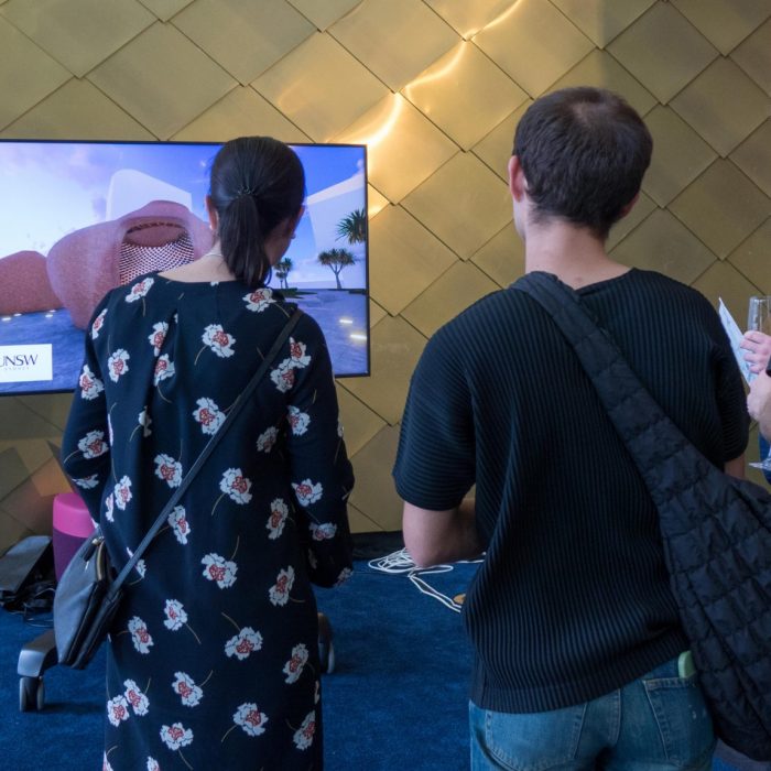 Guests and team members mingling around visual presentation and socialising in foyer of John Clancy Auditorium UNSW Sydney 
