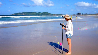 Kristen Splinter on the beach carrying a measuring device