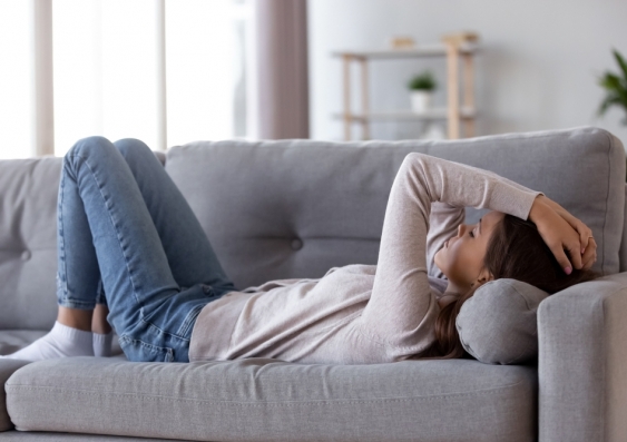 Person lying down on sofa looking tired