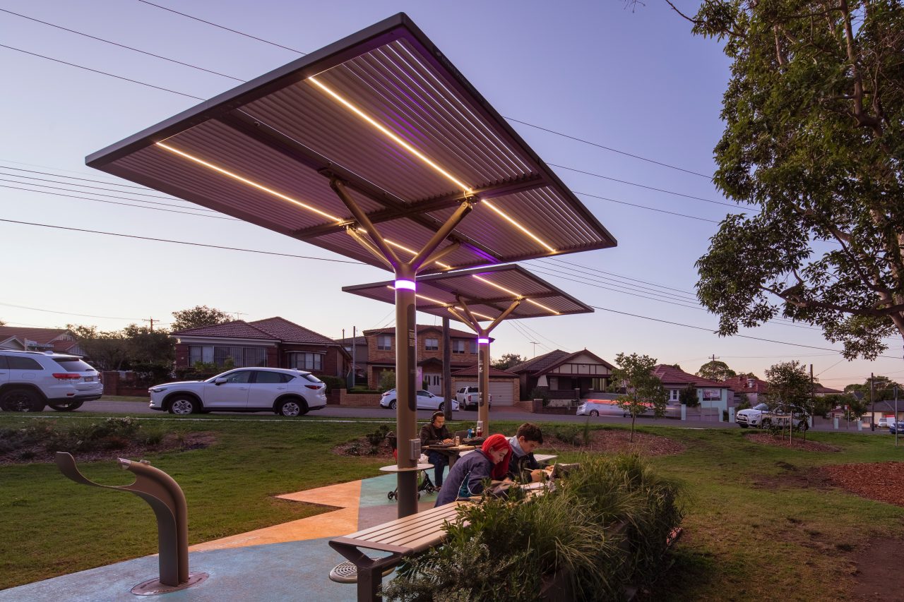 Outdoor shelter in suburban park with people sitting at tables
