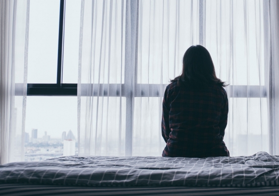 Woman sitting alone in room looking at window