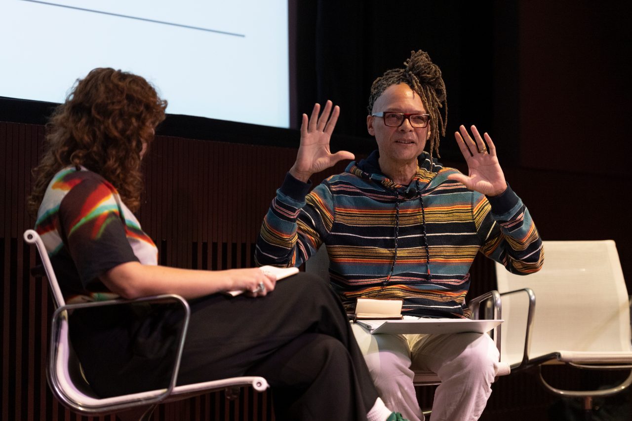 Two people in conversation on stage one with their hands up