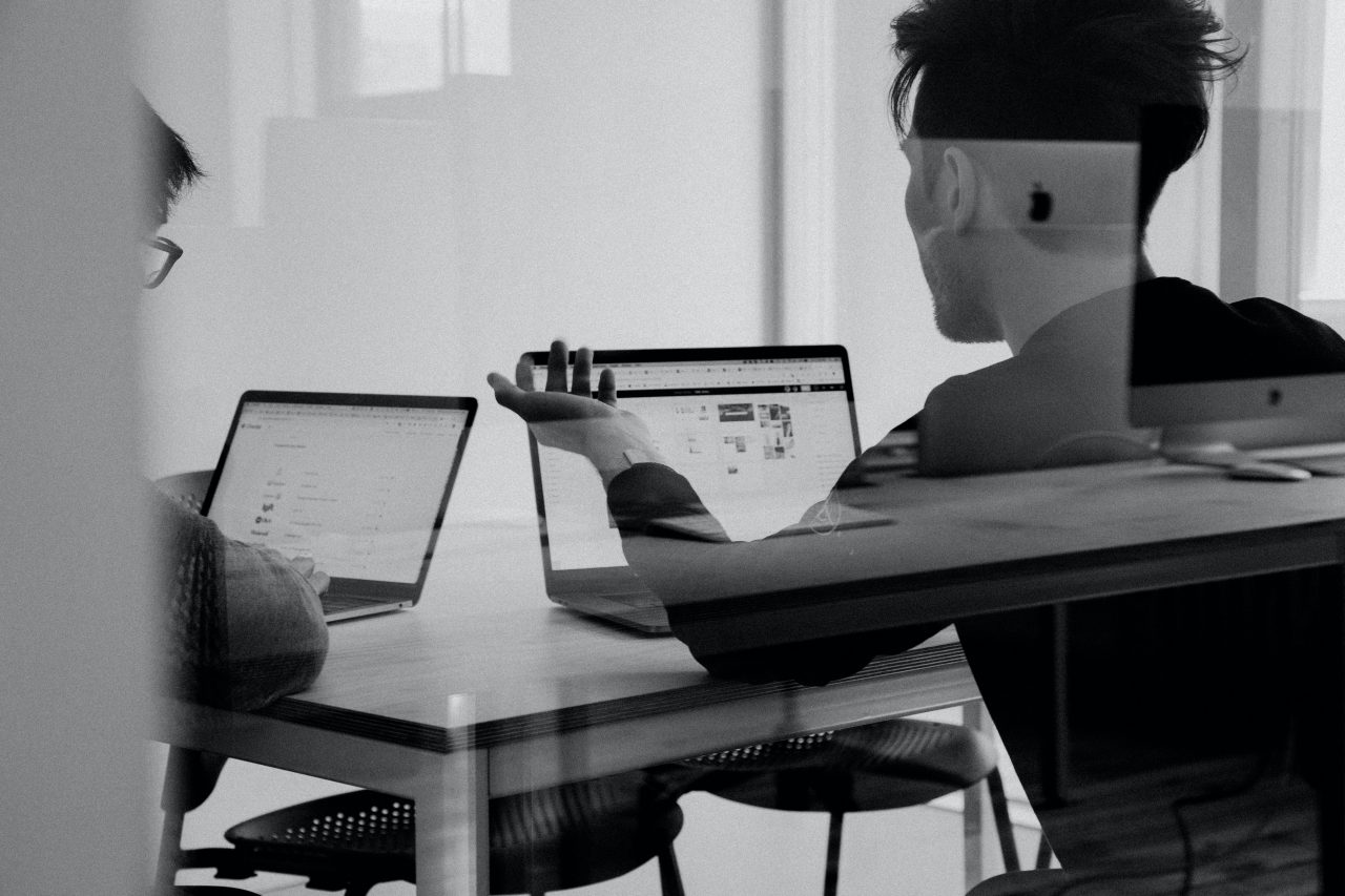 Black and white photo of two people working on laptops