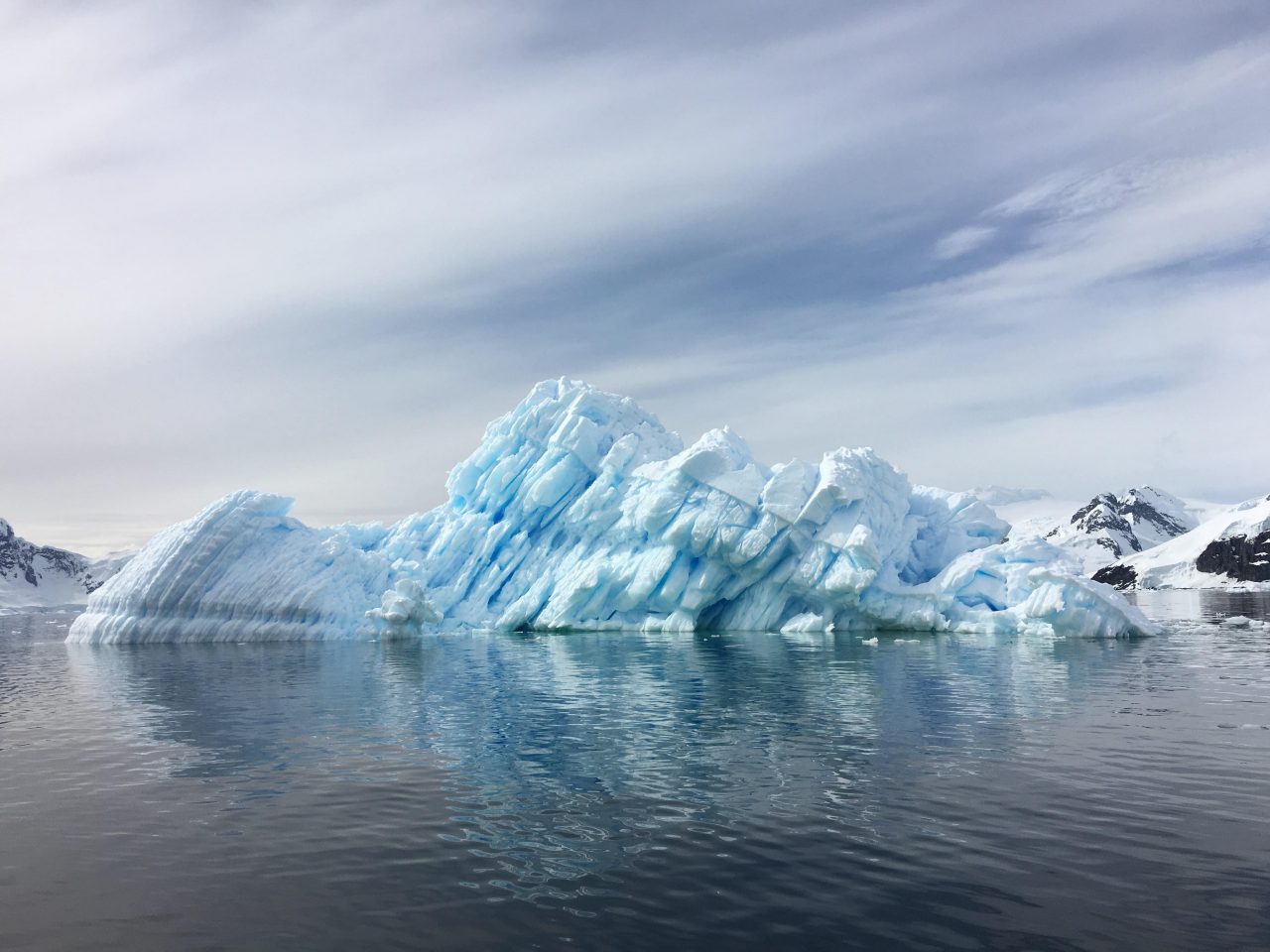 Iceberg floating on grey ocean with overcast sky