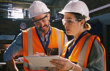 two engineers using a digital tablet together in an industrial place of work