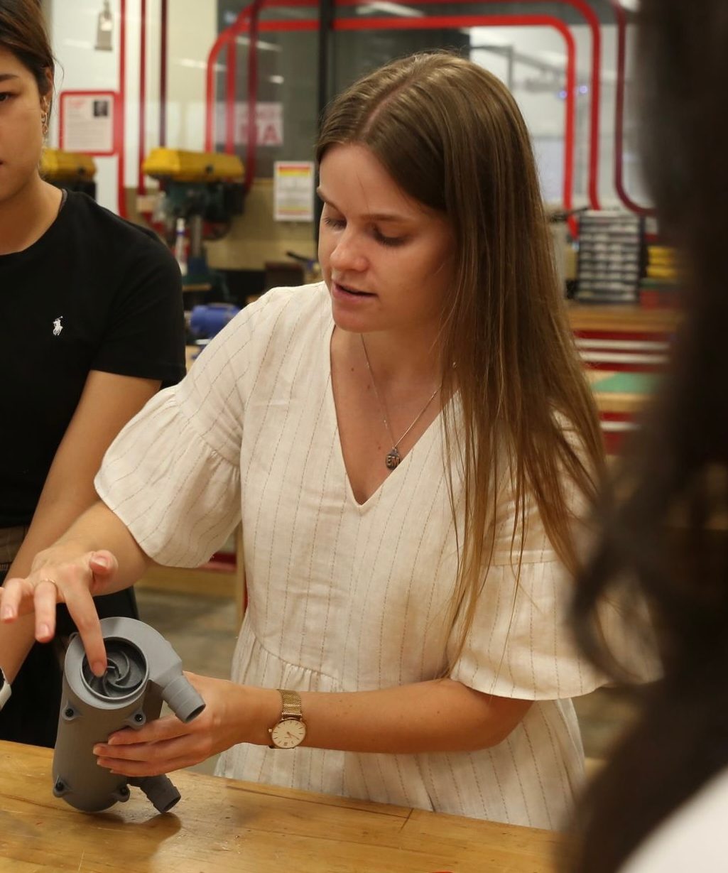 Young woman (Emily) explaining engineering project to industry professionals.