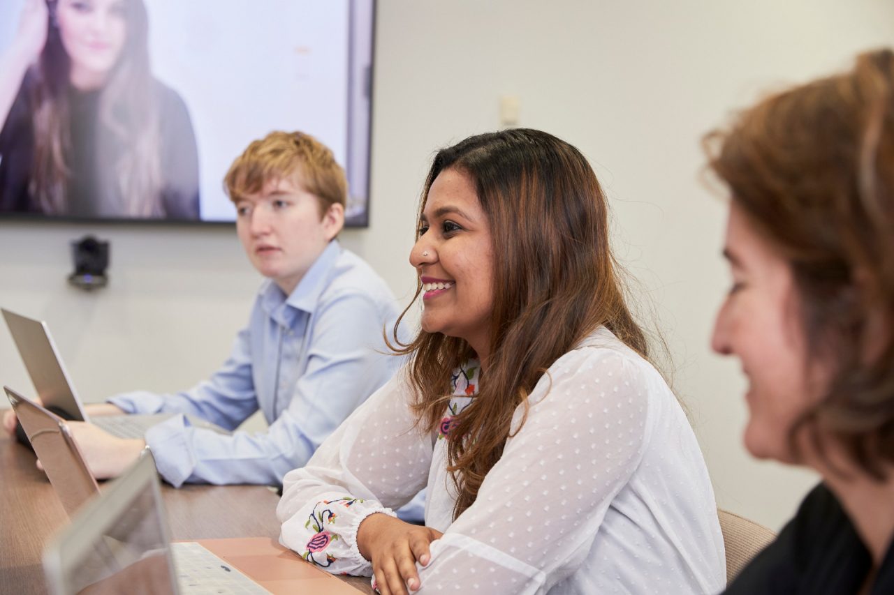 Students in Law PhD Room, around a table with laptops and tv screen