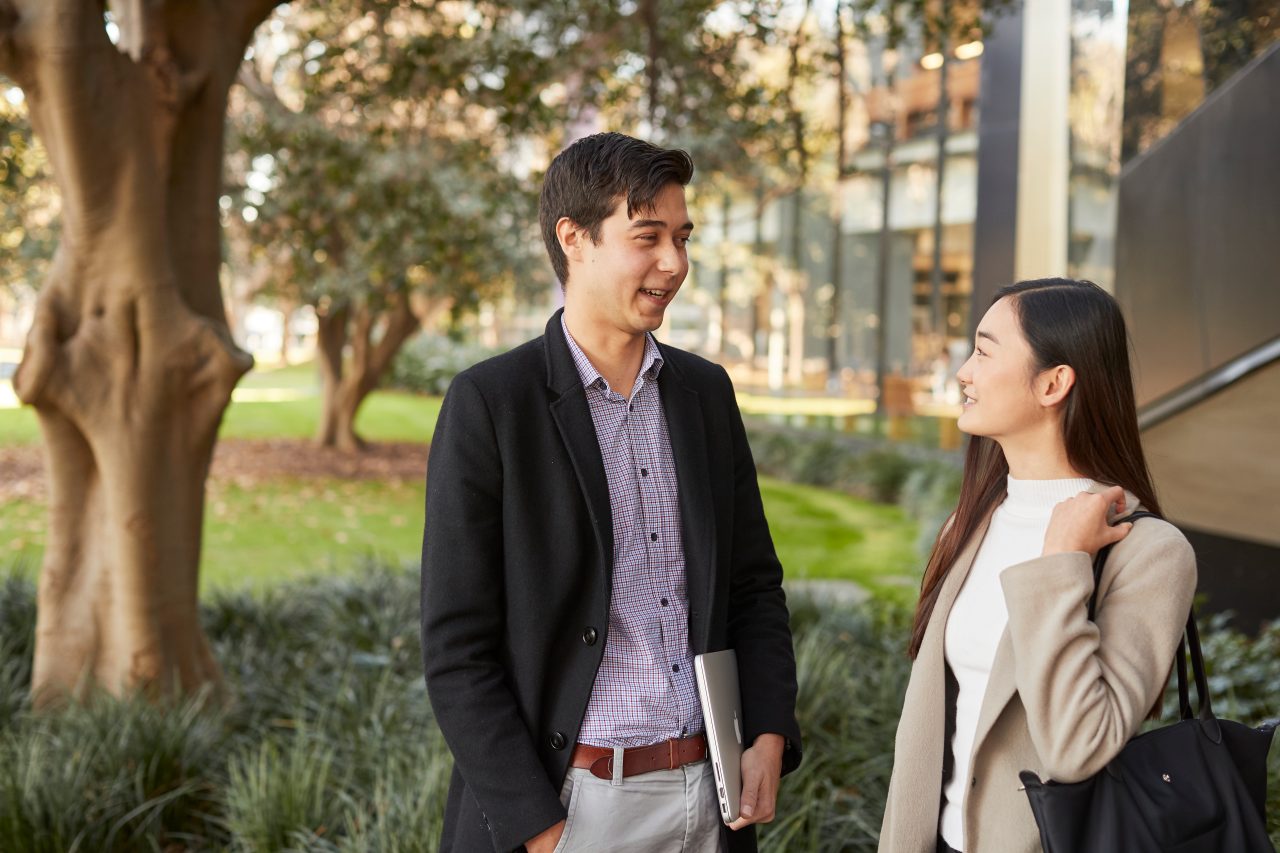 Law student couple standing together in front of Law Building, trees and greenary in background