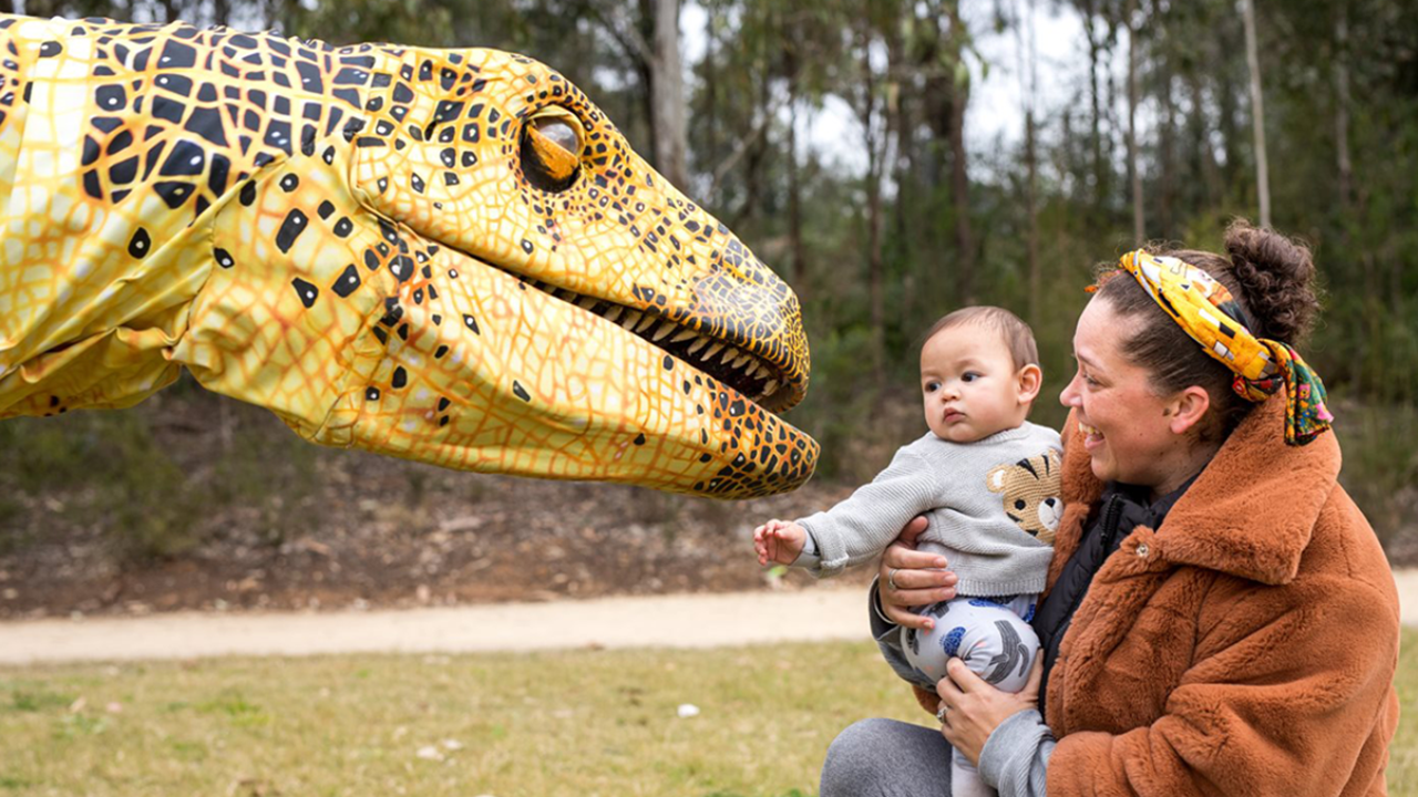 Baby in front of fake dinosaur
