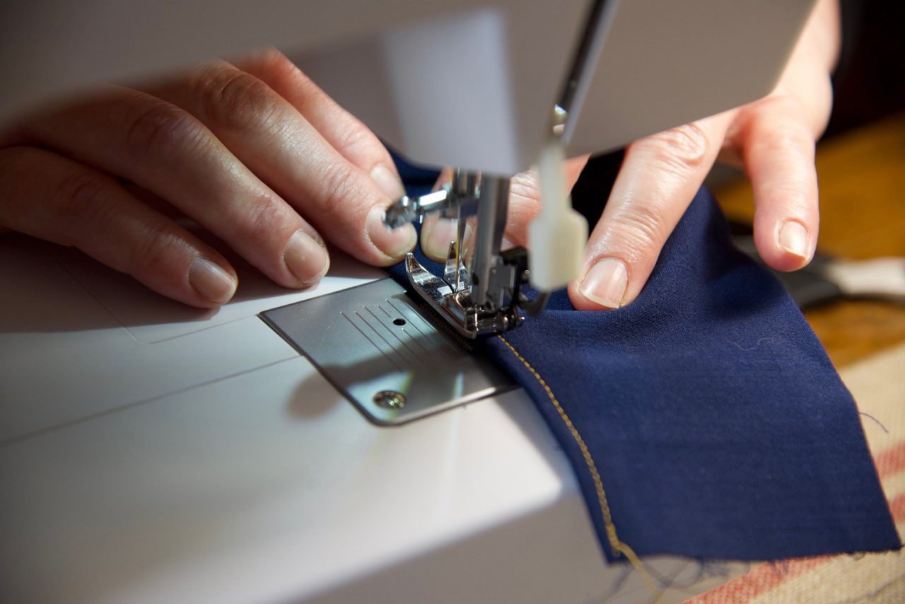 A person's hands shown making a mask on a sewing machine