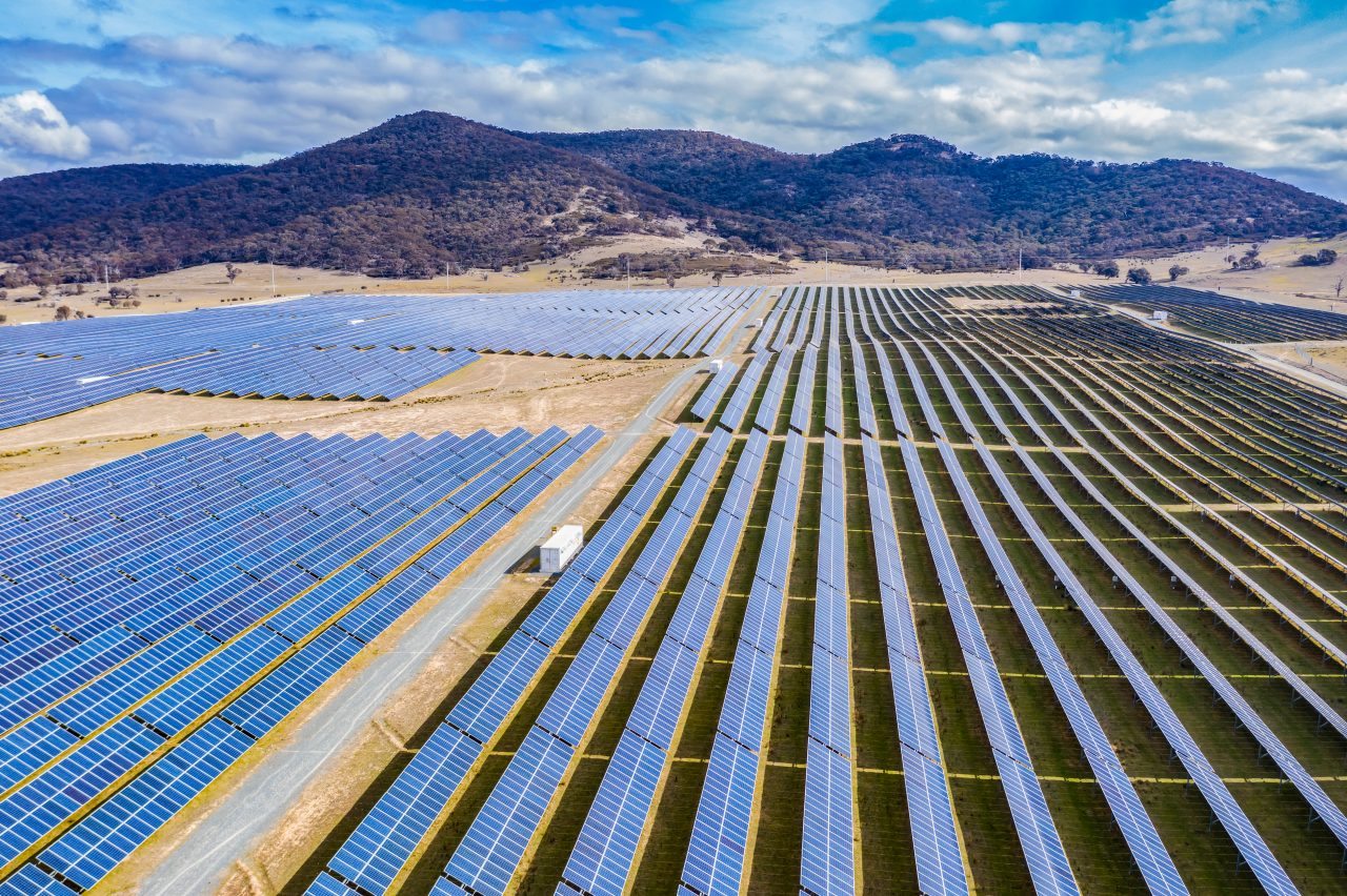 Multiple rows of solar cells in front of mountains at a solar energy farm near Canberra