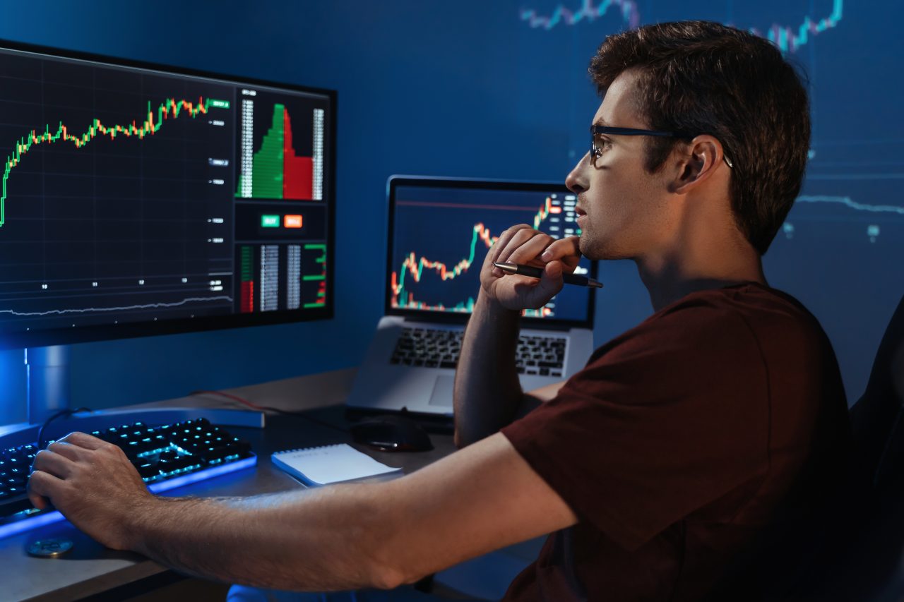 A young man looks at a cryptocurrency trading screen
