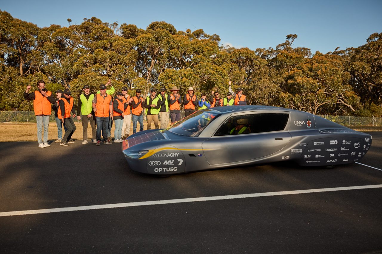 Students standing behind the Sunswift 7 car at the Australian Automotive Research Centre
