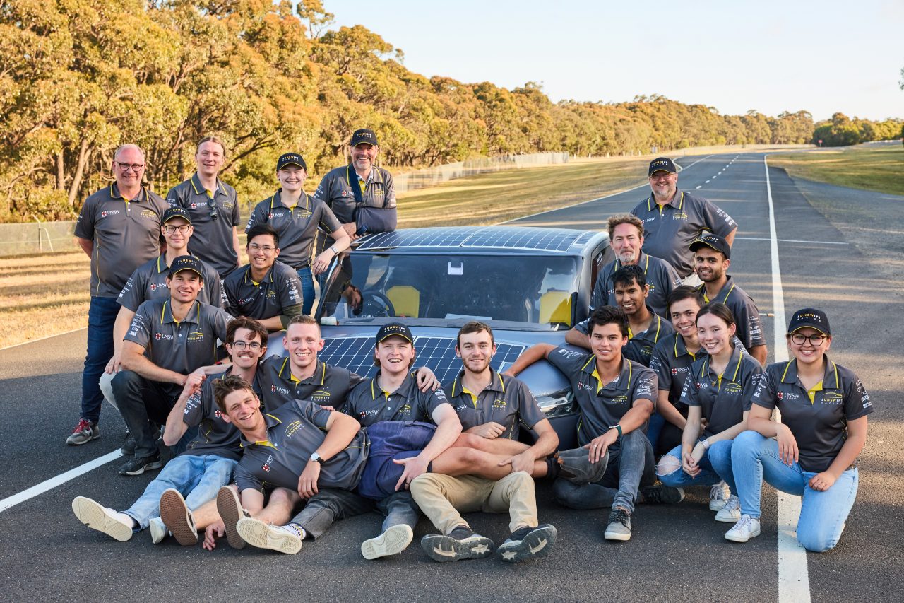 The Sunswift 7 racing team posing with  the Sunswift 7 car on the racetrack after their unofficial Guinness World Record attempt