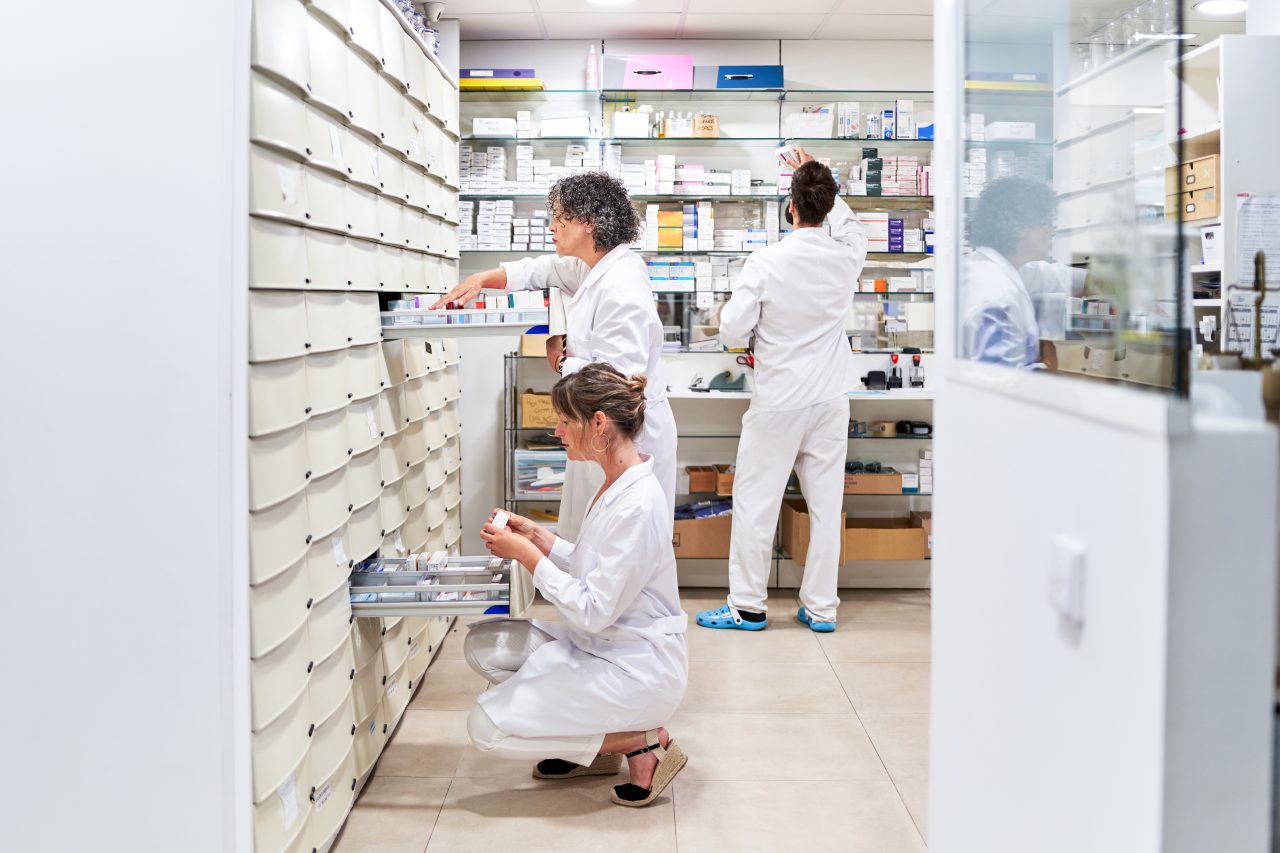 Three pharmacists looking for medicine in the drawers of a pharmacy
