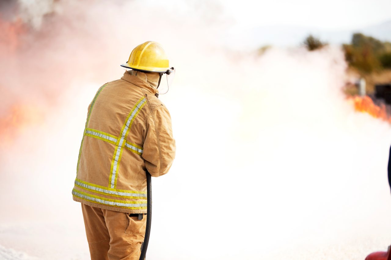 Firefighter spraying firefighting foam at a training facility