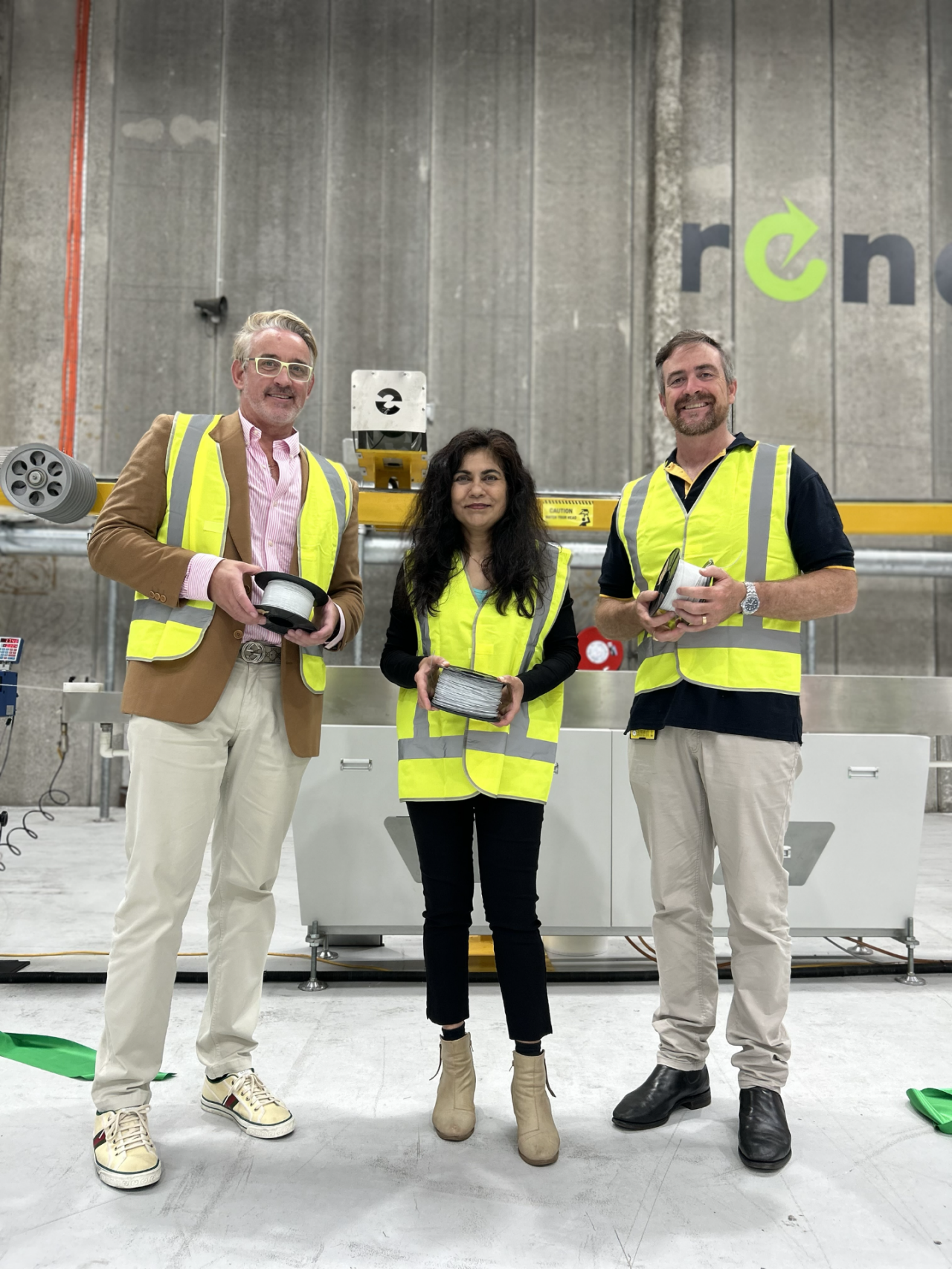 Two men and a woman standing in a printer factory.
