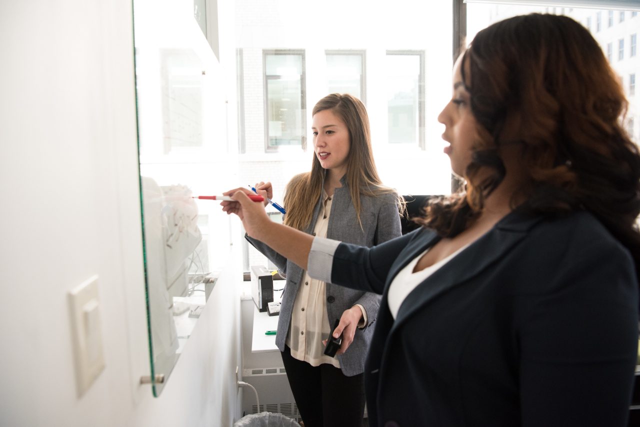 Two young women working at a whiteboard