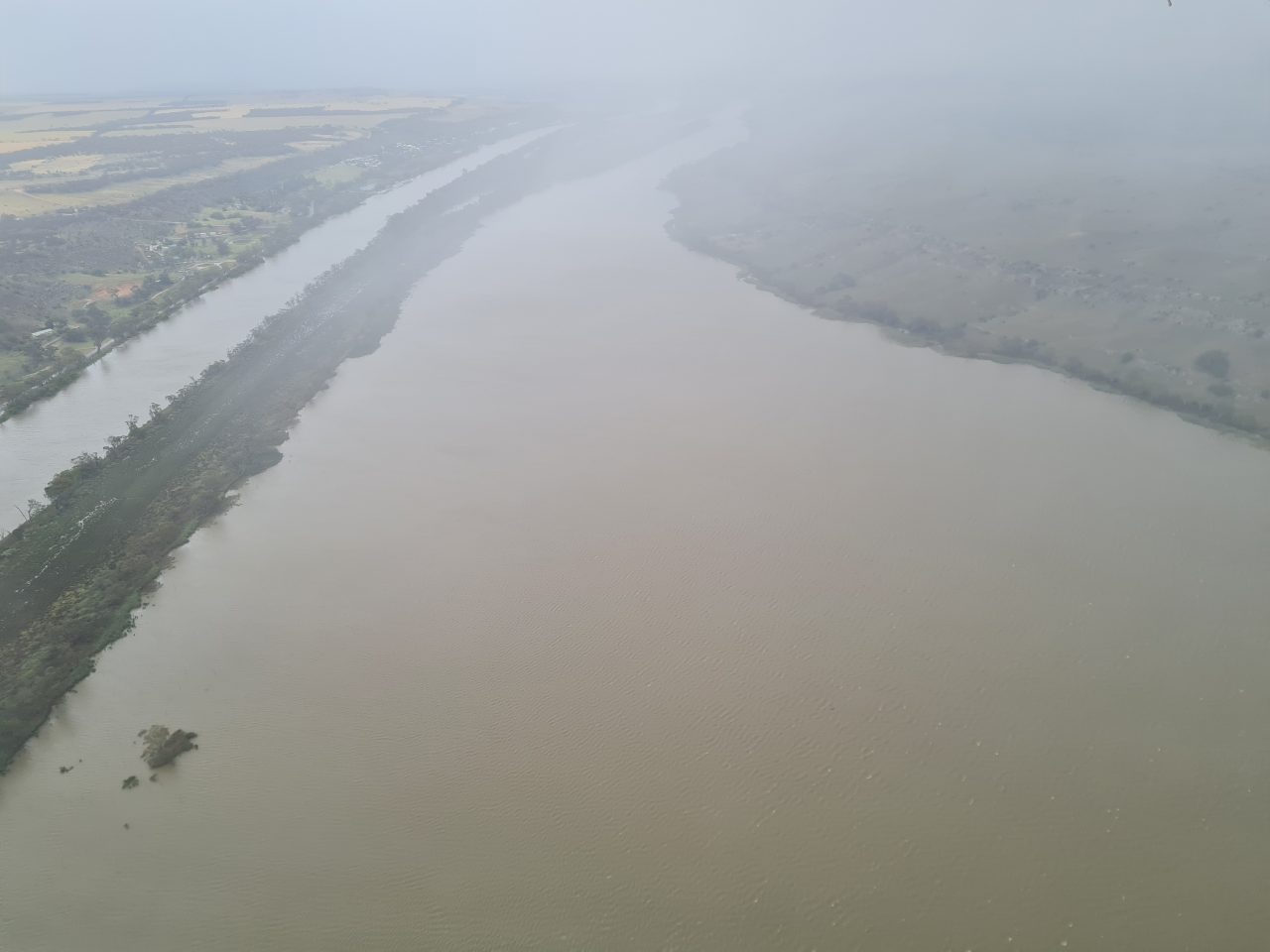 Aerial photo of a very full river channel under cloud.