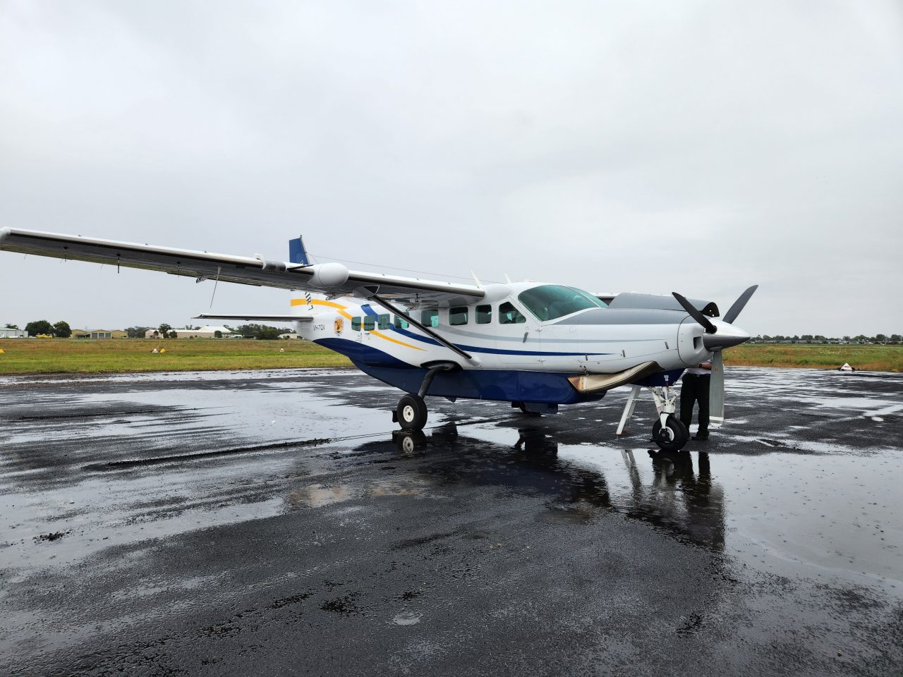 Photo of light aircraft parked on tarmac in a large puddle of water where splashing rain drops are visible.