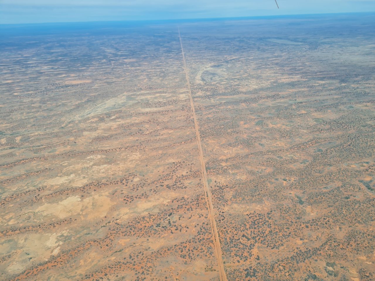Aerial photo of outback desert landscape a long straight border line dissecting the left and right of the image. 