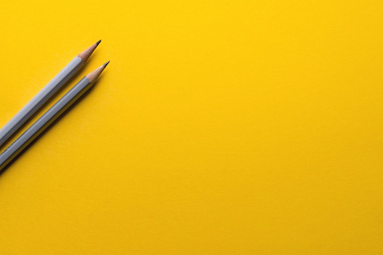 Two grey pencils on yellow background