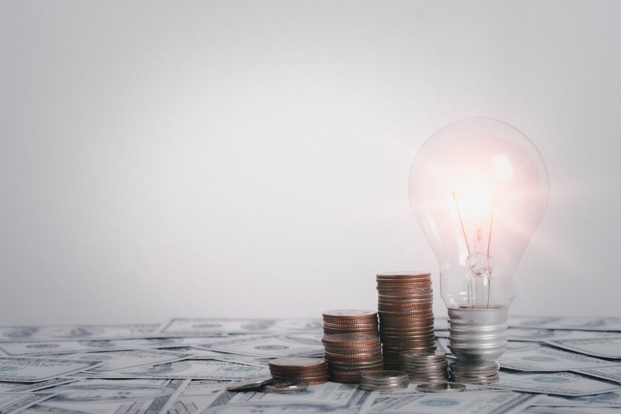 Gold coins growth in stack with light bulb