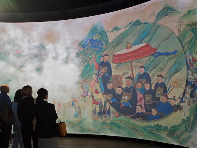 Projection of Chinese art, with people looking at it.