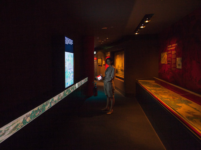 A long shot of the exhibition space, with someone examining the artwork.