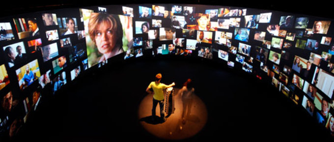 Interior view of the T_Visionarium II, with people standing in the centre looking at the various images projected around them.